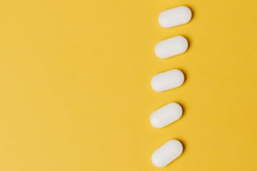white pills in row on yellow background